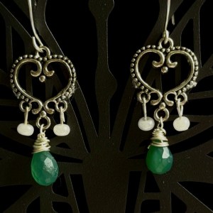 A pair of silver-toned filigree heart chandelier earrings with green chalcedony teardrop stones and small pearl beads — reminiscent of Victorian or bohemian designs.